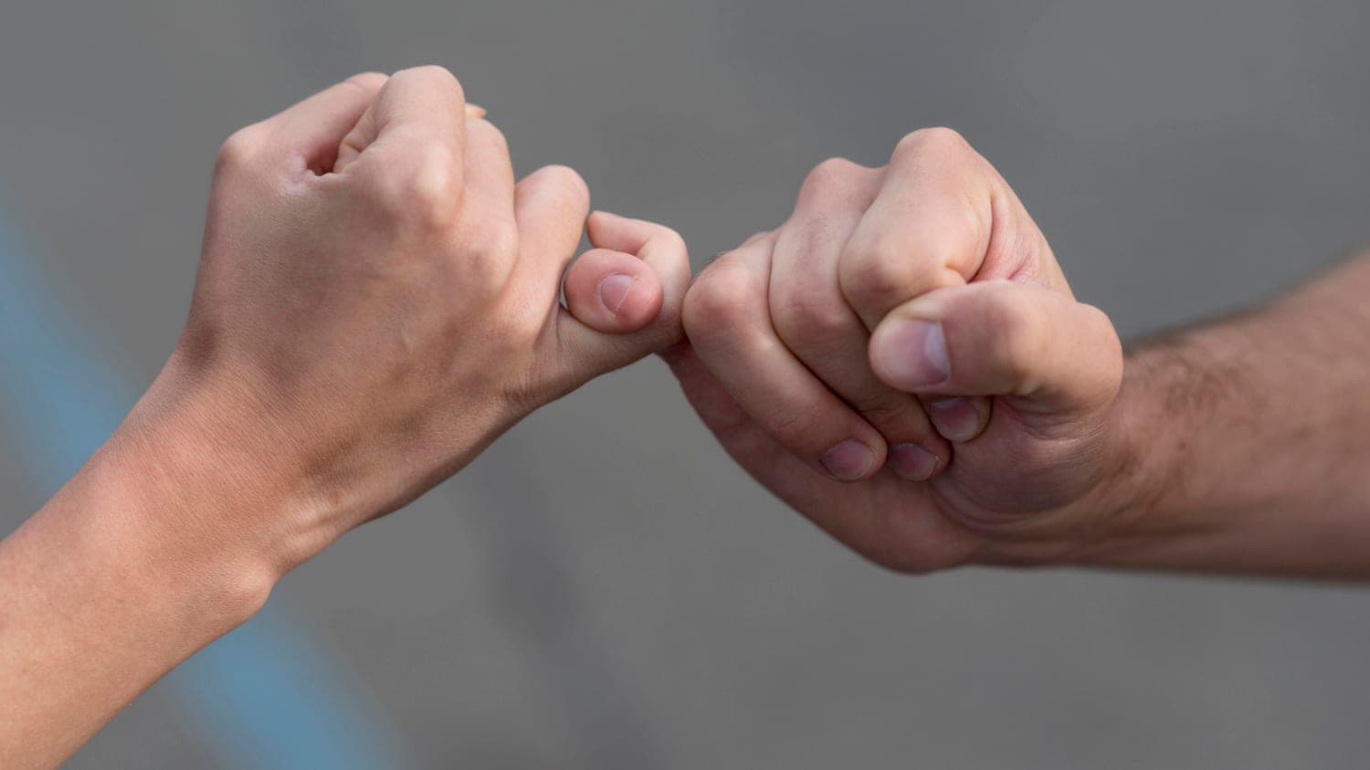 Two people making a pinky-promise gesture